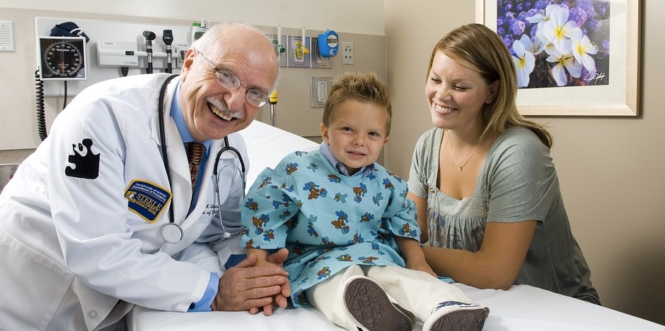 Smiling pediatrician with toddler and parent